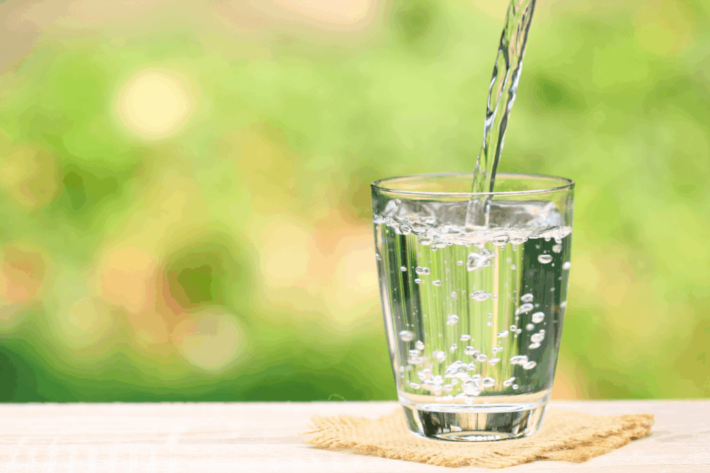 Glas Wasser wird eingeschenkt – ausreichendes Trinken unterstützt Stoffwechsel, Gelenke und das allgemeine Wohlbefinden.