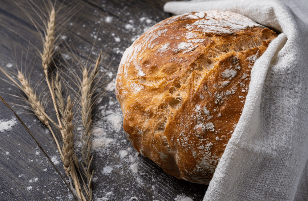 Frisches Brot auf einem Holztisch – Weißmehlprodukte können Entzündungen im Körper fördern.