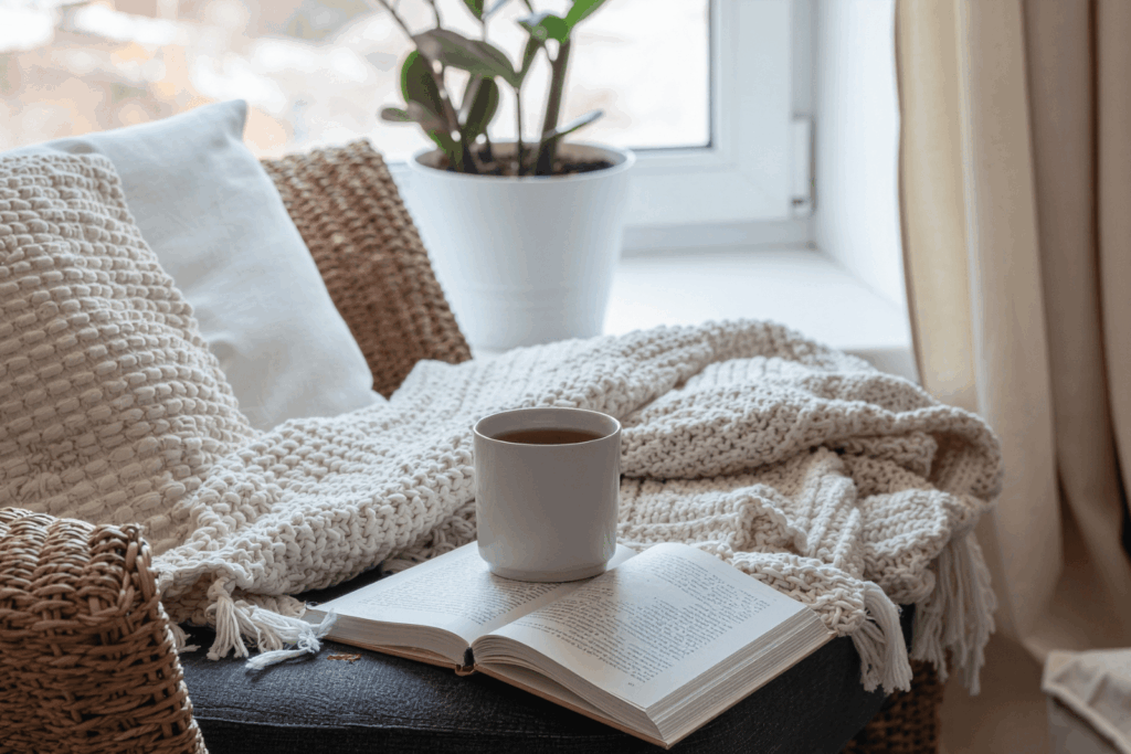 Gemütliche Leseecke mit Decke, Buch und einer Tasse Tee – ein Symbol für Ruhe, Selbstfürsorge und Entlastung bei Rheuma und Fatigue.