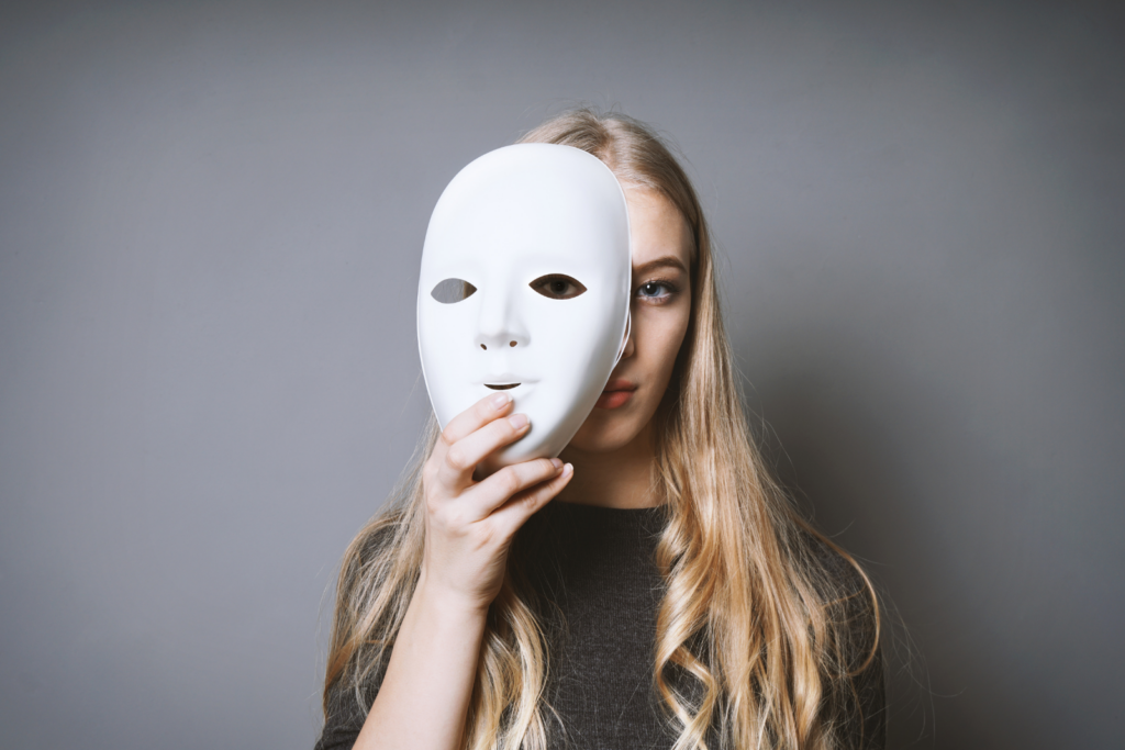 Frau hält eine weiße Maske vor ihr Gesicht